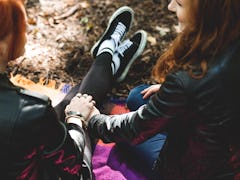 High angle of lesbian girls holding hands, sitting on a blanket in the park