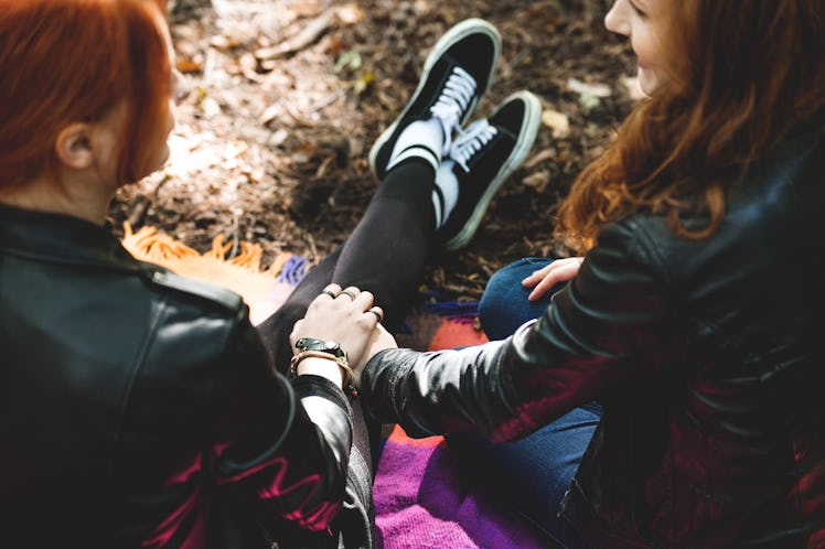 High angle of lesbian girls holding hands, sitting on a blanket in the park