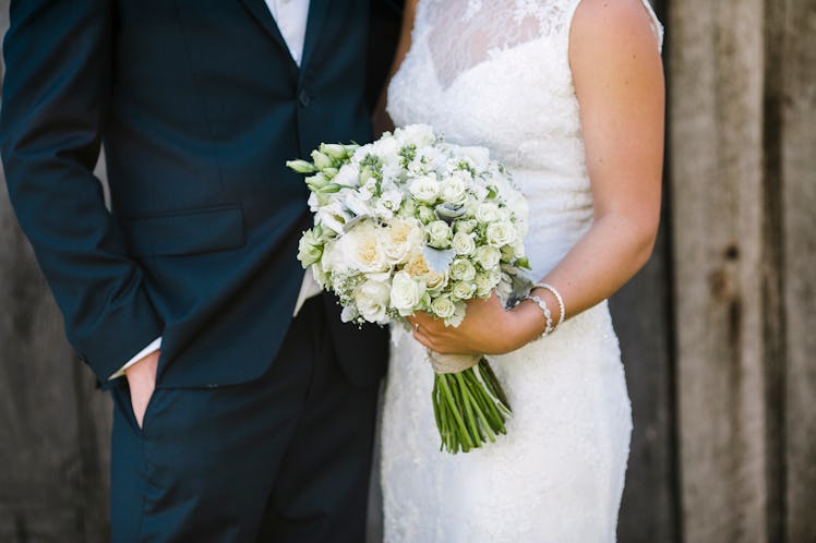 Close up of bride and groom with bride holding classic white and green floral bouquet