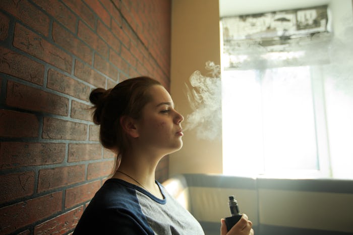 Vape teenager with problem skin. Portrait of young cute girl smoking an electronic cigarette in the...