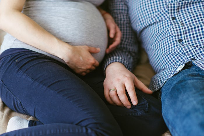 hands of man and woman on a pregnant belly