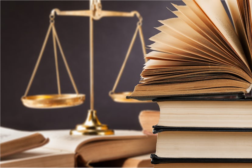 Wooden judges gavel lying on law book, close up