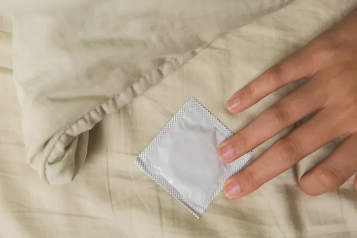 Woman’s hand in bed touch a condom