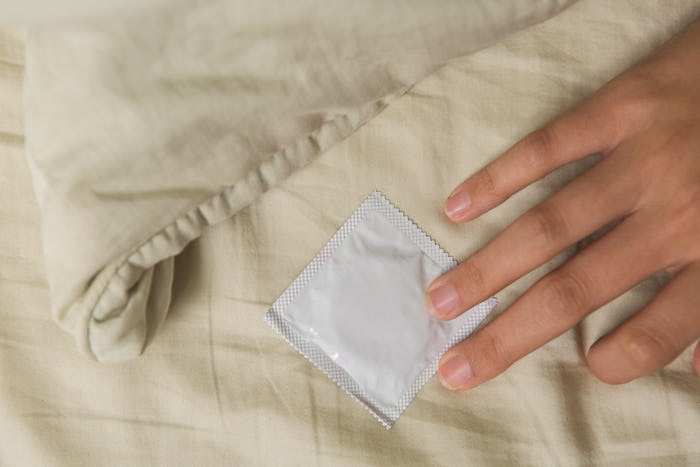 Woman’s hand in bed touch a condom
