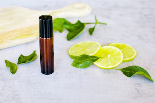 Essential oil roller bottle with lime slices, lime leaves on a concrete bench