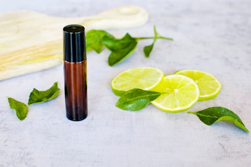 Essential oil roller bottle with lime slices, lime leaves on a concrete bench