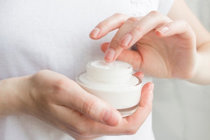 Beauty woman holding a glass jar of skin cream. Skin care concept. Woman taking care of her dry body...