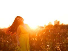 Close-up portrait of beautiful young adult woman in the sunlight at sunset. Pretty girl is smiling. ...