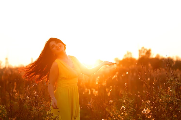 Close-up portrait of beautiful young adult woman in the sunlight at sunset. Pretty girl is smiling. ...