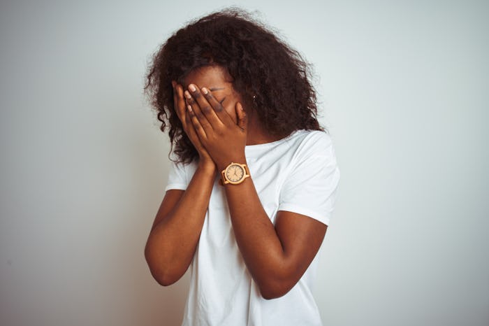 Young african american woman wearing t-shirt standing over isolated white background with sad expres...