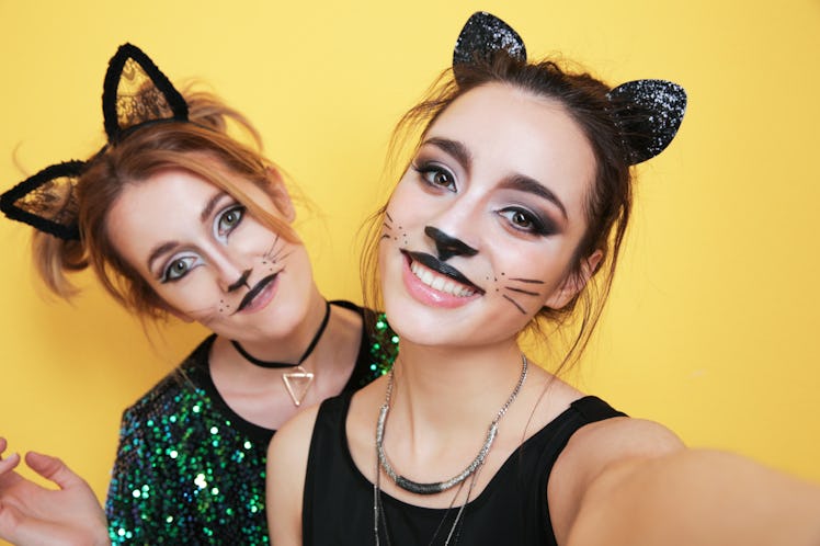 Beautiful young women with cat makeup and ears on color background