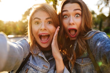 Portrait of two shocked screaming girls making funny faces while taking a selfie outdoors