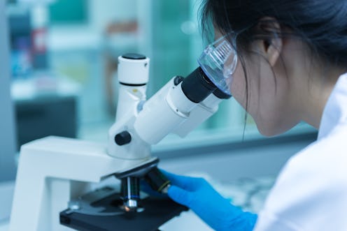 Young asian scientist looking through a microscope in a laboratory.Thailand people doing some resear...