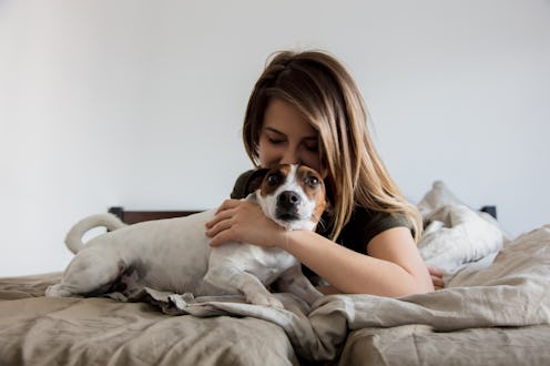 Woman have a fun with dog in a bed