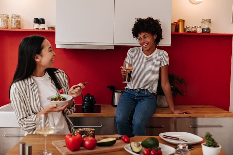 Women in stylish clothes having fun and communicating in kitchen at dinner with champagne