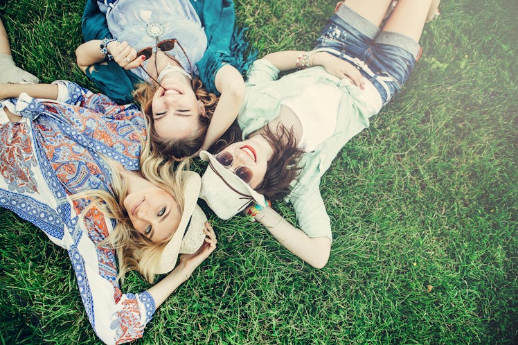 Trendy Hipster Girls Relaxing on the Grass . Summer lifestyle portrait of three hipster women laying...