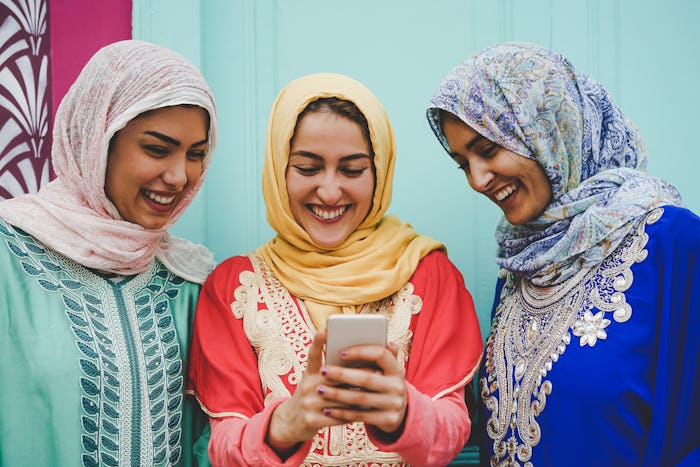 Happy Muslim women watching on mobile smart phone in the college - Arabian young girls having fun wi...