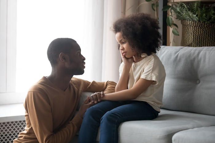 Loving african American father talk with upset preschooler daughter helping with problem, caring bla...