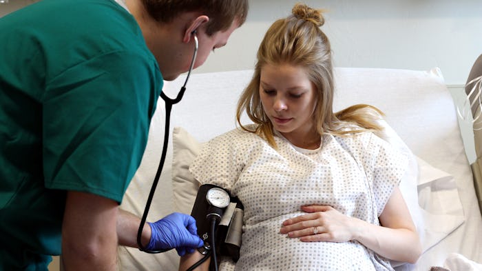 pregnant woman getting blood pressure taken by male nurse in hospital