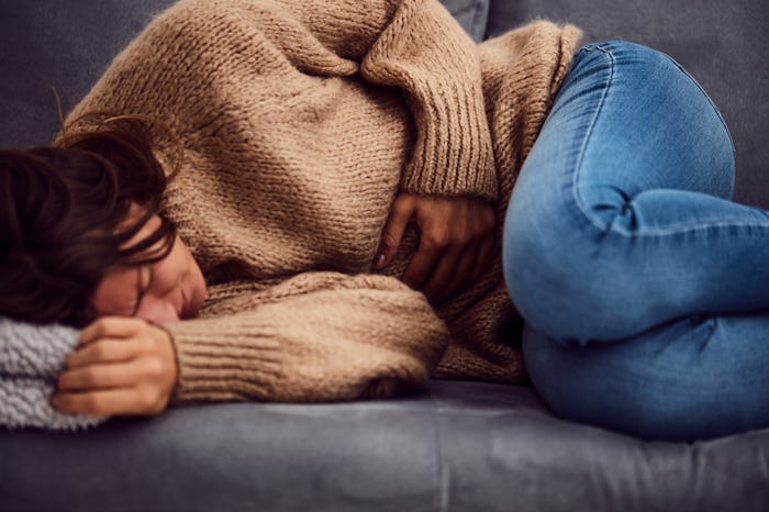 Woman having stomach issues / problems while lying on the couch.