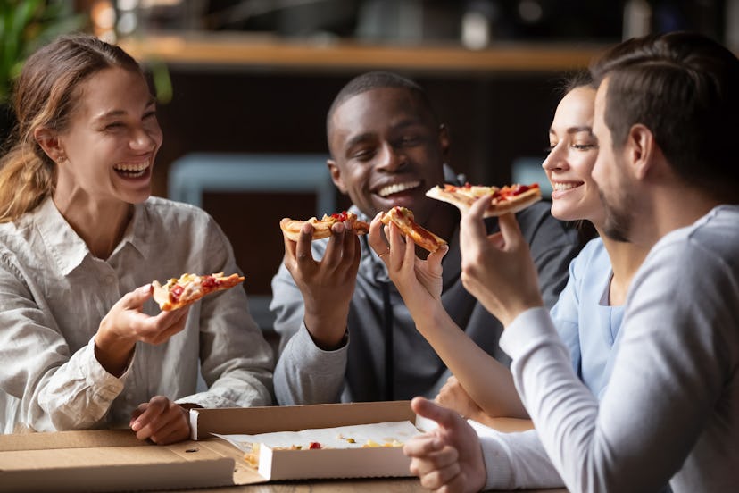 Cheerful multiracial happy best friends couples laugh at funny joke eating pizza in cafe together, h...