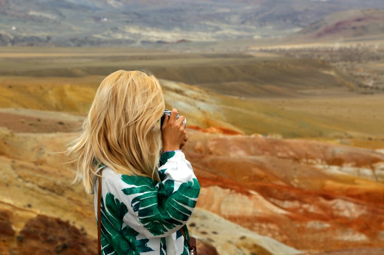 Blond woman traveller taking photo of red mountains in Altai in Russia. Valley of Mars landscapes in...