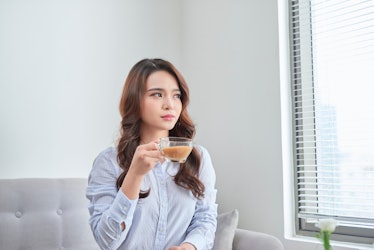 Cheerful woman relaxing in sofa and drinking tea