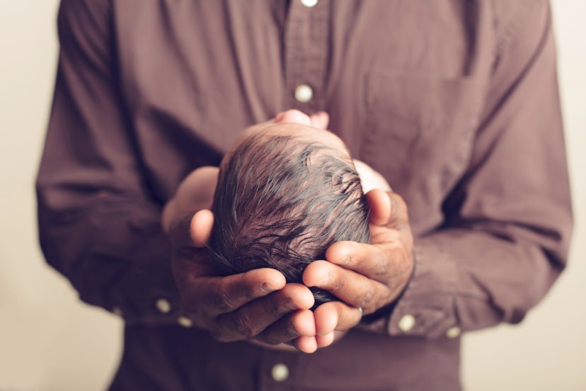 Newborn cradled in his father's hands