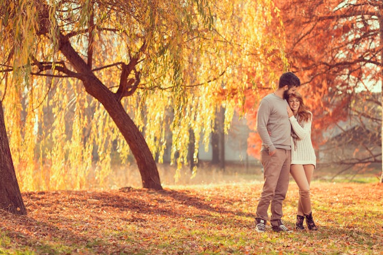 Young couple in love holding hands and walking through a park on a sunny autumn day