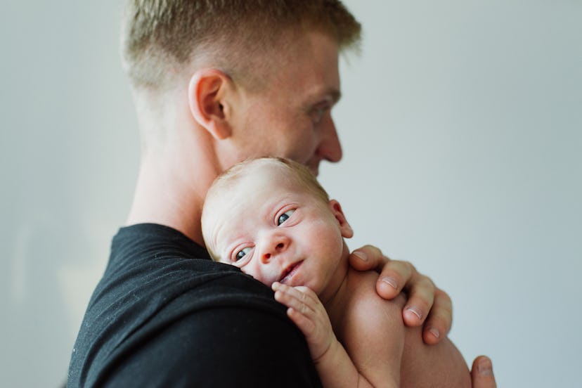 A man holds a newborn in his arms. Young dad holds the newborn in his arms.