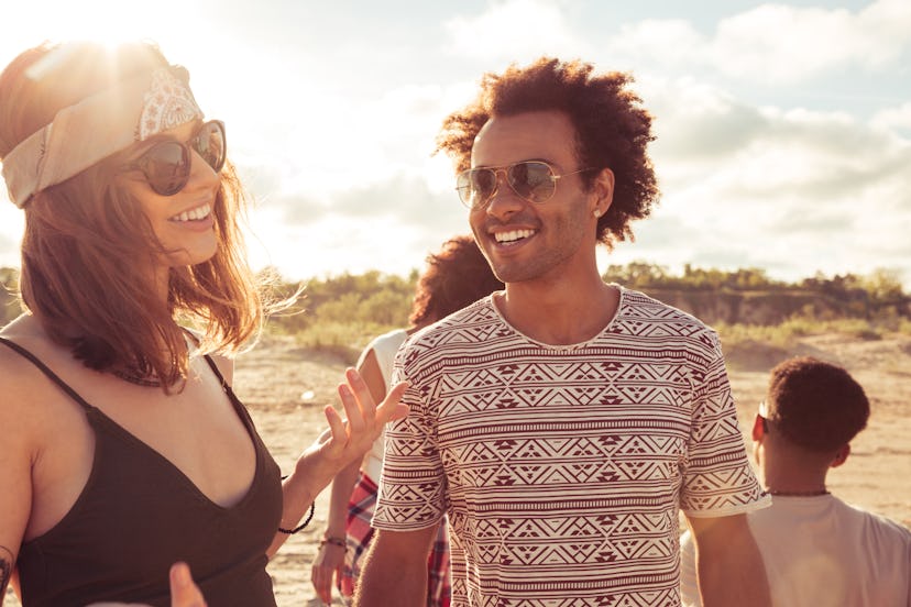 Image of happy young loving couple friends walking outdoors on the beach talking with each other.