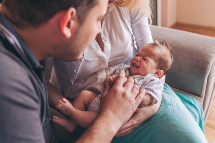 Portrait of a cute newborn baby crying. Young family with baby
