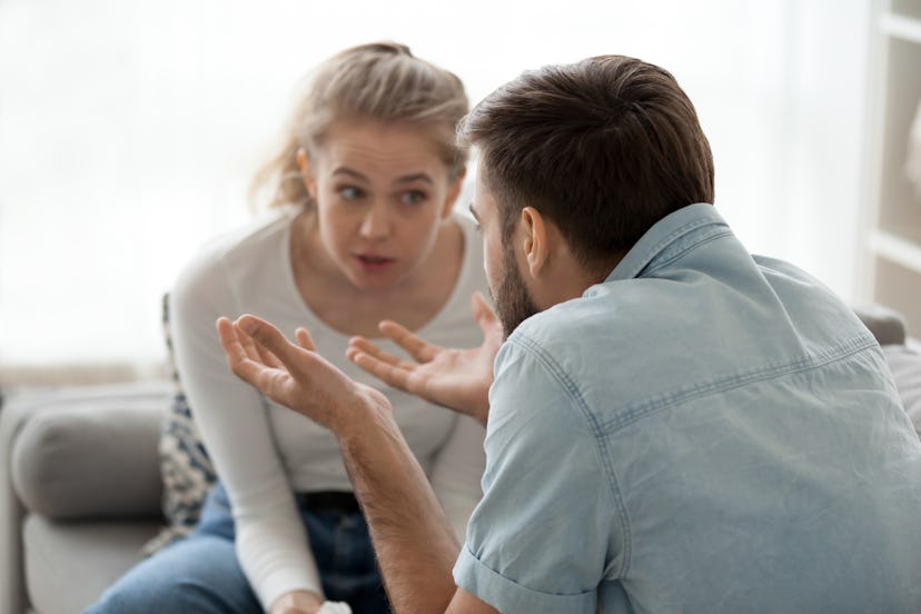 Millennial couple arguing sitting on couch at home, emotional husband gesturing proving his point of...