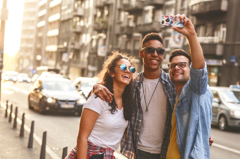 Group of friends hangout at the city street.They embrace each other and doing selfie.