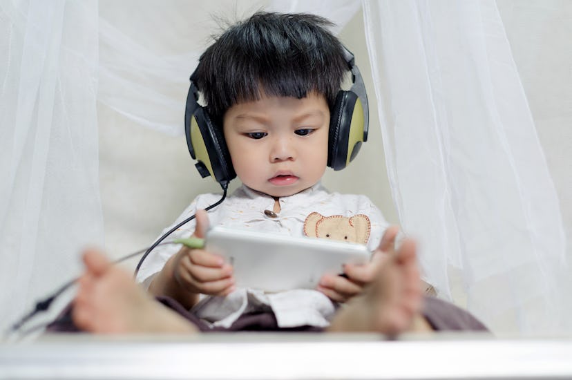 cute little Baby Boy enjoying watching and listening Music form smart phone with head phones,holding...