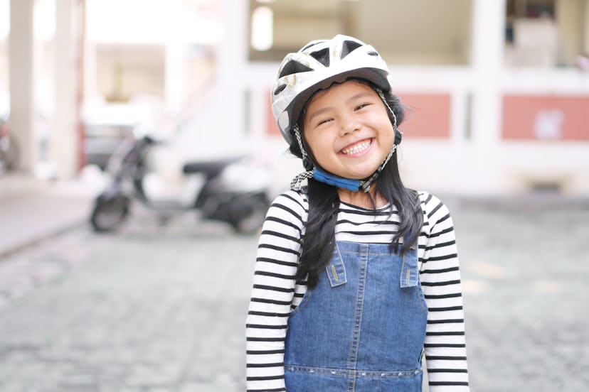 Asian child cute or kid girl wear white motorcycle or bike helmet with happy smiling white teeth for...