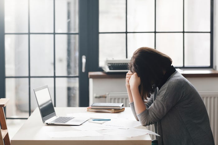 Female entrepreneur sitting in office and looks confused with laptop on desk. Business problems, cri...