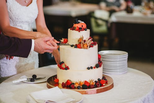 The bride and groom cut a beautiful wedding white cake decorated with berries, fizalis and pumpkins....