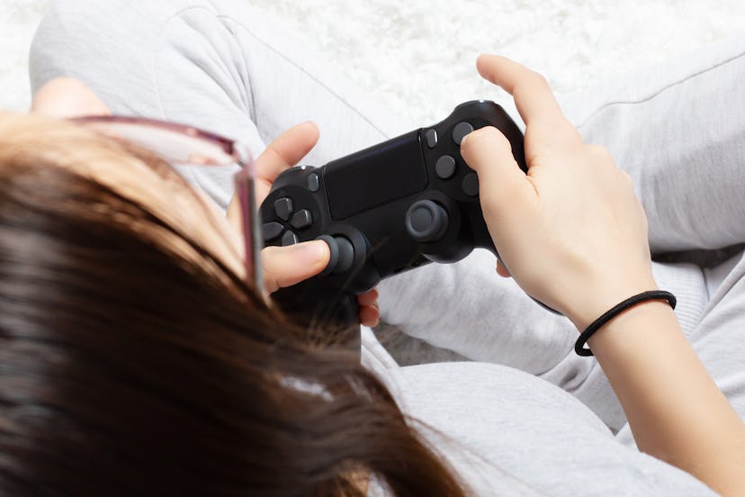 Female hands hold joystick, a young girl plays a video game