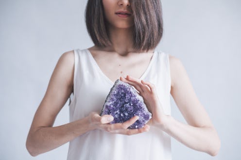 This woman holding an amethyst could pair the crystal with lavender essential oil to de-stress.