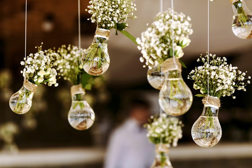 Original wedding floral decoration in the form of mini-vases and bouquets of flowers hanging from th...