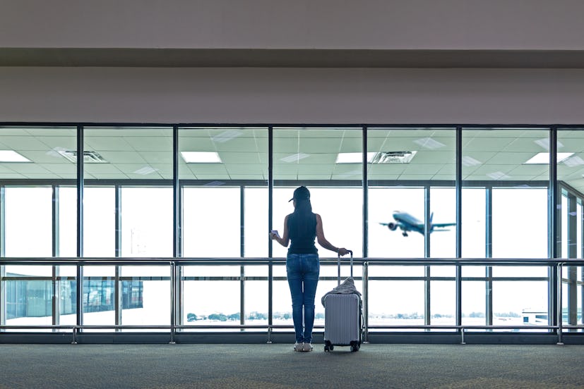 Traveler women plan and backpack see the airplane at the airport glass window, Asian tourist hold ba...