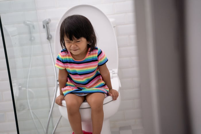 portrait of toddler push it hard while pooping in the toilet