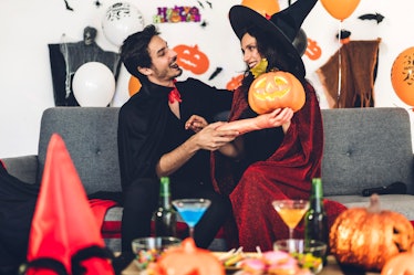 Couple having fun holding pumpkins and wearing dressed carnival halloween costumes and makeup posing...