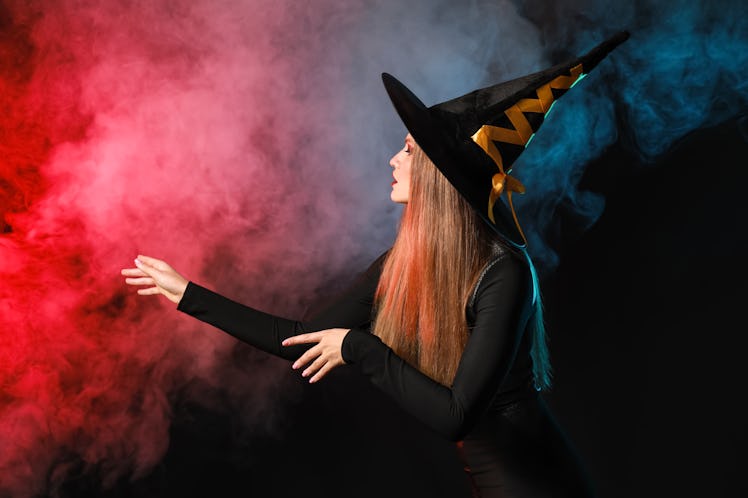 Beautiful woman dressed as witch for Halloween on dark background