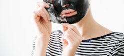 Young woman in striped half sleeve removing bamboo charcoal peel off facial mask at home. Over white...