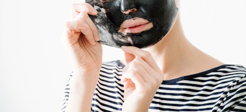 Young woman in striped half sleeve removing bamboo charcoal peel off facial mask at home. Over white...