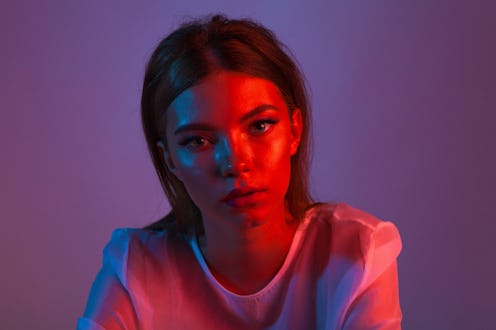 Neon close up portrait of young woman. Studio shot. Model posing in purple, red and pink lights. Fa...
