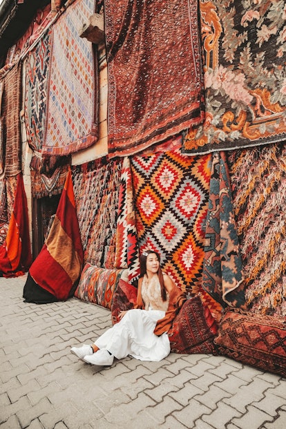 Happy travel woman with amazing colorful carpets in Local carpet shop ,Goreme. Cappadocia Turkey
