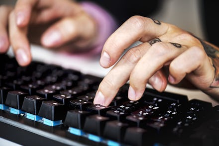 Hands with tattoo typing on a keyboard